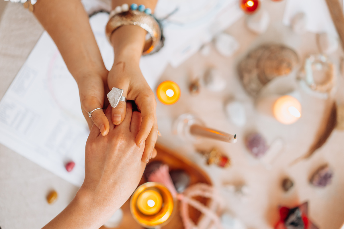 A Person Holding Another Person's Hand Above the Table with Lighted Candles